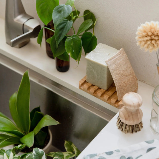 Bamboo Waterfall Self-Draining Soap Dish surrounded by leafy plants on kitchen counter| Eco Friendly Earth Ahead